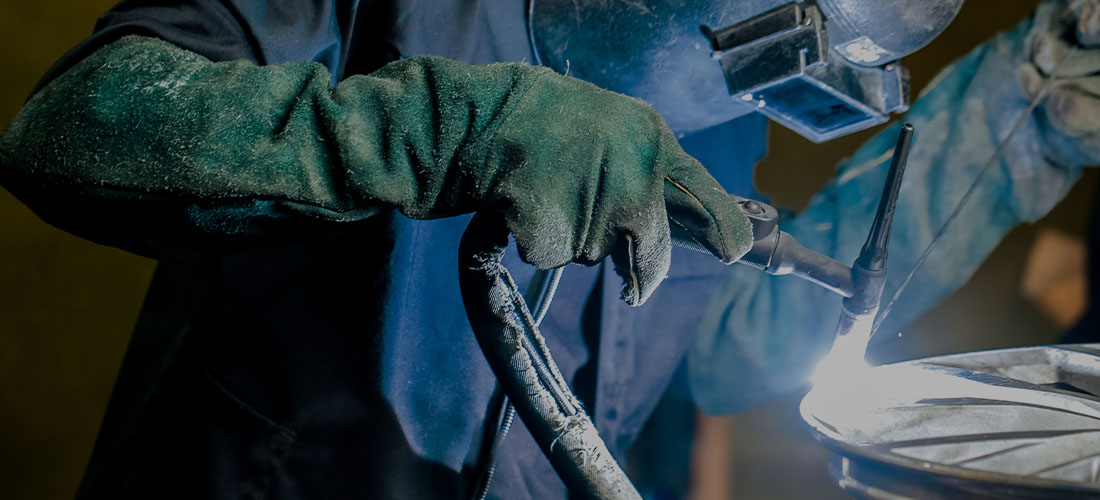 Man using a welding machine to refurbish an alloy wheel