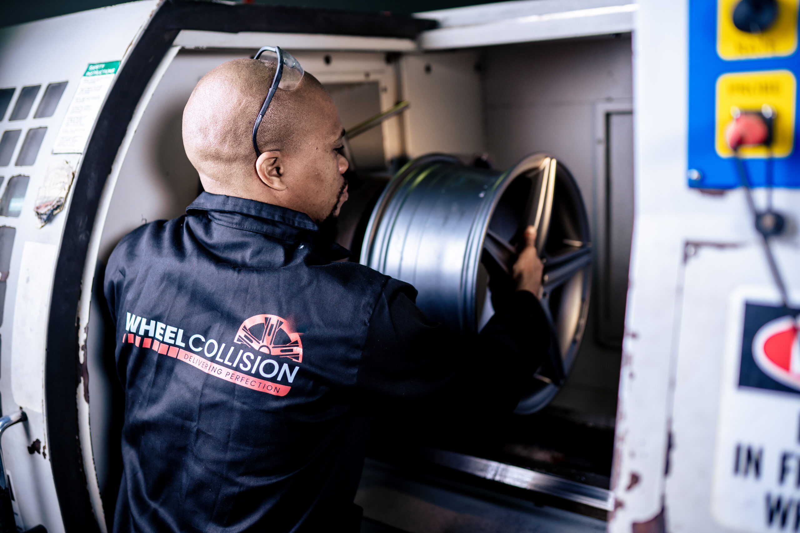 Wheel Repair Specialist placing a car wheel in an X-Ray machine for straightening