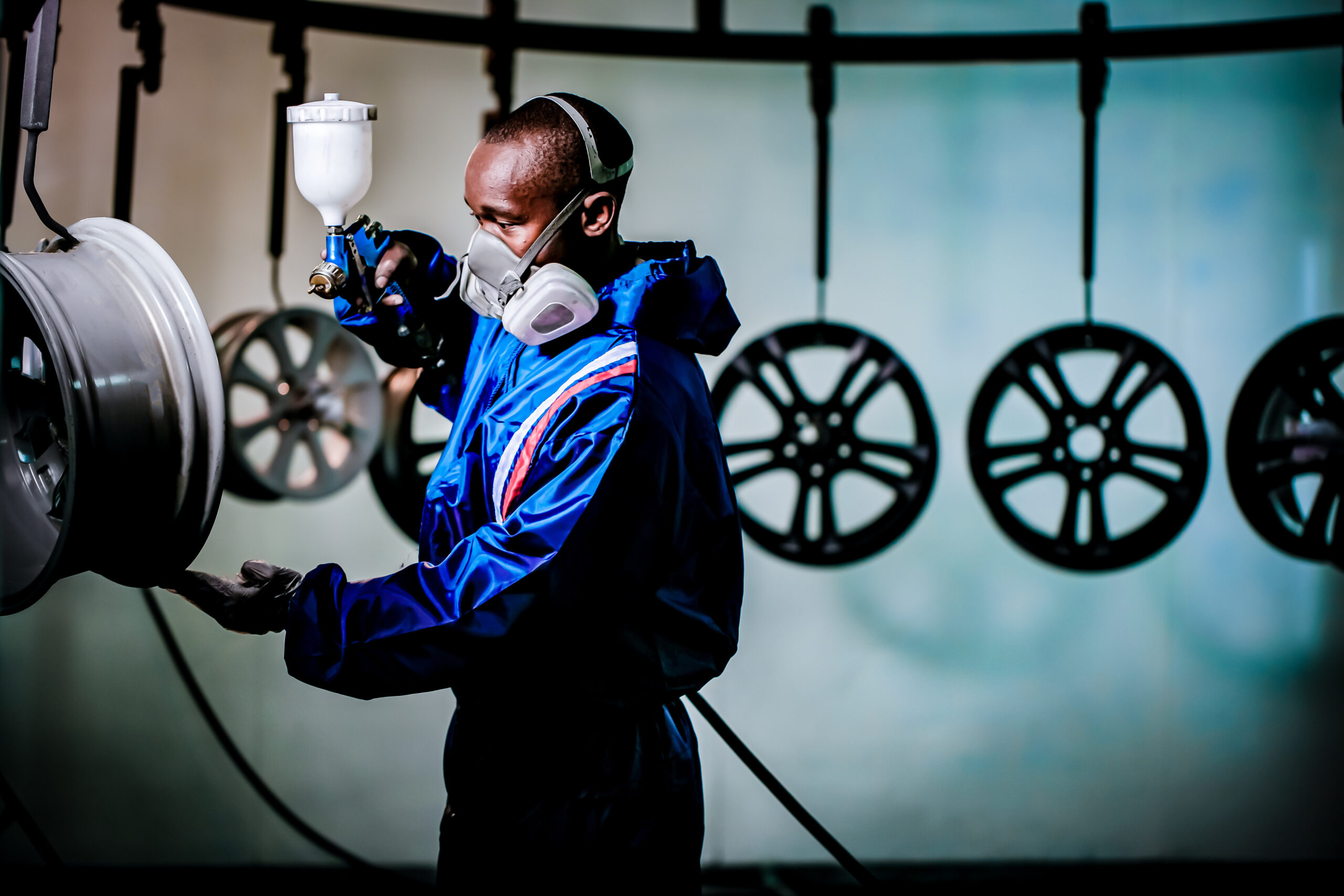 Man spraying paint on an alloy wheel at the Wheel Collision refurbishment center